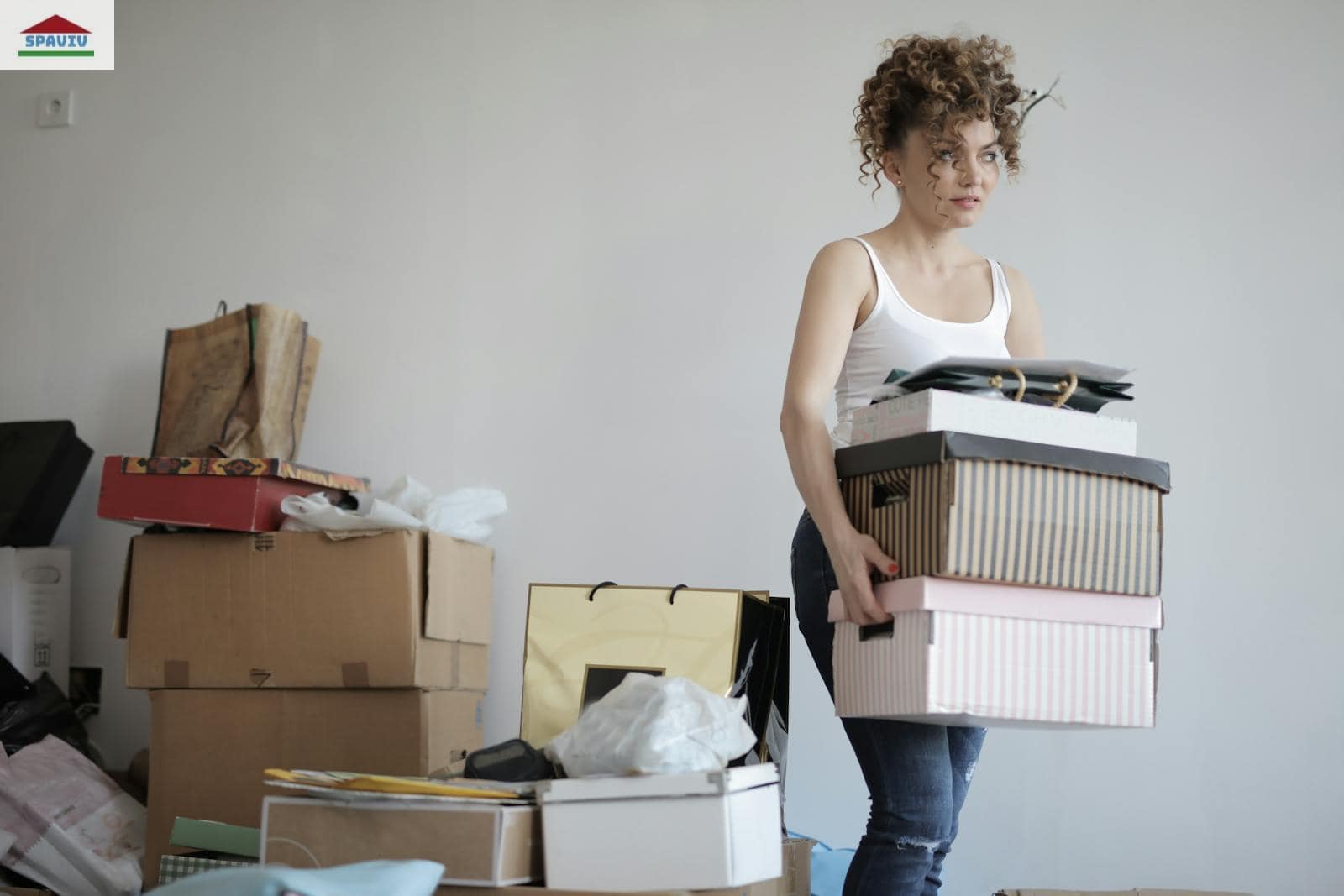 Concentrated woman carrying stack of cardboard boxes for relocation