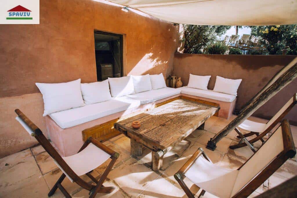 Inviting outdoor patio with rustic wooden furniture and white cushions, perfect for relaxation.