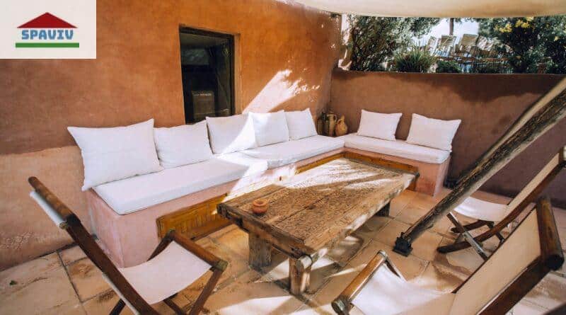 Inviting outdoor patio with rustic wooden furniture and white cushions, perfect for relaxation.