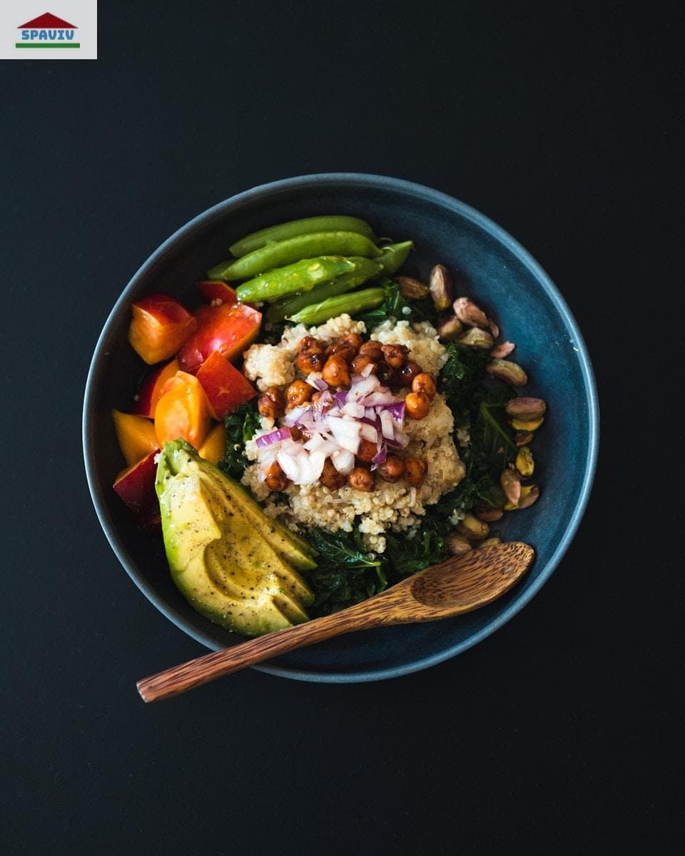a blue bowl filled with vegetables and a wooden spoon